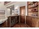 Wet bar area with built-in wine refrigerators, custom cabinetry, hardwood floors, and granite countertops at 7475 E Gainey Ranch Rd # 4, Scottsdale, AZ 85258