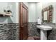 Charming powder room with decorative mirror, custom mosaic tile, pedestal sink, and wooden door at 7475 E Gainey Ranch Rd # 4, Scottsdale, AZ 85258