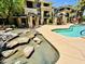 Community pool with lush greenery, a grill, rock features, and seating areas at 7601 E Indian Bend Rd # 1049, Scottsdale, AZ 85250
