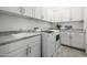 Laundry room with modern white cabinets, utility sink, gray countertops and stainless steel appliances at 8138 E Jacaranda St, Mesa, AZ 85207