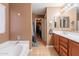 Bright bathroom featuring a soaking tub, single vanity, with access to a walk-in closet at 9352 W Pioneer St, Tolleson, AZ 85353