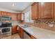 Kitchen area with stainless steel appliances, brown cabinetry, and tile backsplash at 9352 W Pioneer St, Tolleson, AZ 85353