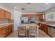 An open kitchen features wood cabinets, stainless steel appliances, mosaic tile backsplash, and an island with bar seating at 9352 W Pioneer St, Tolleson, AZ 85353