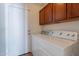 Functional laundry room with a washer and dryer, featuring upper wood cabinets at 9352 W Pioneer St, Tolleson, AZ 85353