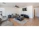 Comfortable living room features tile floors, ceiling fan, a leather couch, and a modern entertainment center at 9352 W Pioneer St, Tolleson, AZ 85353