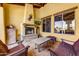Inviting covered patio with an outdoor fireplace, comfortable seating, tile accents, and views of the lush landscaping at 9415 N 124Th St, Scottsdale, AZ 85259