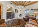 Comfortable living room with rustic wood beam ceiling, stucco fireplace, and large windows providing ample natural light at 9415 N 124Th St, Scottsdale, AZ 85259
