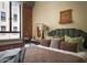 Bedroom with exposed brick, comfortable bed with green headboard, and bright window with city views at 114 W Adams St # 907, Phoenix, AZ 85003