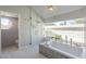 Bright bathroom with soaking tub, large windows, glass enclosed shower, and tiled floor at 12537 N 76Th Pl, Scottsdale, AZ 85260