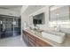 Vanity with granite countertop, double sinks, dark cabinets, tv, and modern lighting at 12537 N 76Th Pl, Scottsdale, AZ 85260