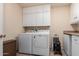 Laundry room with modern washer and dryer with overhead storage cabinets at 14828 N Skokie Ct, Phoenix, AZ 85022