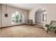 Spacious living room with neutral carpet, shuttered arched window, and classic armchairs at 14828 N Skokie Ct, Phoenix, AZ 85022