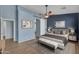 Staged bedroom featuring a ceiling fan, wood floors, neutral colors, and barn door to closet at 15564 W Mescal St, Surprise, AZ 85379