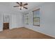 This light-filled bedroom features a ceiling fan, soft carpet, and two bright windows at 15564 W Mescal St, Surprise, AZ 85379