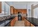 Modern kitchen featuring wood cabinets, black countertops, tiled backsplash, and stainless steel appliances at 15564 W Mescal St, Surprise, AZ 85379