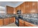 Modern kitchen featuring wood cabinets, black countertops, tiled backsplash, and stainless steel appliances at 15564 W Mescal St, Surprise, AZ 85379