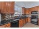 Modern kitchen features wood cabinets, black countertops, tiled backsplash, and stainless steel appliances at 15564 W Mescal St, Surprise, AZ 85379