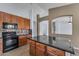 Open kitchen featuring wood cabinets, granite countertops, black appliances, and a center island at 15564 W Mescal St, Surprise, AZ 85379