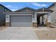 Charming exterior elevation featuring a two-car garage, desert landscaping, and inviting front porch at 17290 W Daley Ln, Surprise, AZ 85387