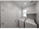 Well-lit laundry room with washer, dryer, overhead shelving, and a door at 17290 W Daley Ln, Surprise, AZ 85387