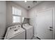 Well-lit laundry room with washer, dryer, overhead shelving, and a window at 17290 W Daley Ln, Surprise, AZ 85387
