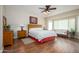 Spacious main bedroom with wood floors, ceiling fan, bay window, and a comfortable seating area at 21003 N Circle Cliffs Dr, Surprise, AZ 85387