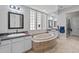 Luxurious bathroom features double sinks, a soaking tub, and natural light from decorative windows at 30434 N Palo Brea Dr, Scottsdale, AZ 85266