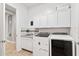 Functional laundry room equipped with modern washer and dryer units, cabinets, and a utility sink at 30434 N Palo Brea Dr, Scottsdale, AZ 85266