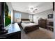 Nicely decorated bedroom with ceiling fan, windows and dresser near a flat-screen tv on a gray wall at 31006 W Weldon Ave, Buckeye, AZ 85396