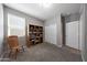 Carpeted bedroom with a bookshelf, chair, and closet has a large window to let in light and a ceiling light at 31006 W Weldon Ave, Buckeye, AZ 85396