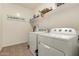 Well-lit laundry room with modern washer and dryer, and ample shelving for storage at 36203 N Urika Dr, San Tan Valley, AZ 85140