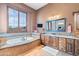 This elegant bathroom includes a soaking tub, wooden cabinets and travertine countertops at 42037 N Bradon Way, Phoenix, AZ 85086