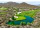 Aerial view of a lush green golf course featuring a serene pond and stunning desert mountain backdrop at 42037 N Bradon Way, Phoenix, AZ 85086