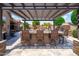 Outdoor kitchen with a bar, grill, and shaded pergola, perfect for enjoying meals and gatherings by the pool at 42037 N Bradon Way, Phoenix, AZ 85086