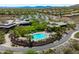 The aerial view showcases a clubhouse with a curved pool, sun loungers, desert landscaping, and community homes at 42037 N Bradon Way, Phoenix, AZ 85086