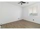 Bright bedroom with modern ceiling fan, wood-look flooring, window and minimalist decor at 46185 W Dutchman Dr, Maricopa, AZ 85139