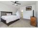 Bright bedroom with ceiling fan and carpet flooring with view into the bathroom at 46185 W Dutchman Dr, Maricopa, AZ 85139