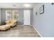 Bright living room featuring neutral walls, wood-look tile flooring, a front door, and a comfortable leather armchair at 46185 W Dutchman Dr, Maricopa, AZ 85139