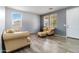 Bright living room with wood-look tile flooring, neutral walls, comfortable furniture and lots of natural light at 46185 W Dutchman Dr, Maricopa, AZ 85139