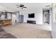 Spacious open-concept living room with a ceiling fan, modern lighting, and cozy carpet at 46185 W Dutchman Dr, Maricopa, AZ 85139