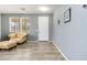 Bright living room featuring neutral walls, wood-look tile flooring, a front door, and a comfortable leather armchair at 46185 W Dutchman Dr, Maricopa, AZ 85139