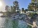 Scenic waterfall cascading into a tranquil pond, surrounded by lush greenery and mature trees at 46185 W Dutchman Dr, Maricopa, AZ 85139