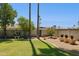 Spacious backyard featuring a lush lawn, mature trees, rock landscaping, and privacy walls at 4711 S Los Feliz Dr, Tempe, AZ 85282