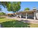 Backyard featuring covered patio with hanging chair, seating and dining areas, lush lawn, and mature trees at 4711 S Los Feliz Dr, Tempe, AZ 85282
