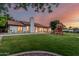 Green backyard featuring a playhouse, surrounded by mature trees under a colorful sky at 5602 W Alameda Rd, Glendale, AZ 85310