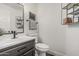 Modern half-bathroom with dark vanity, sleek fixtures, decorative shelving, and a framed mirror at 5602 W Alameda Rd, Glendale, AZ 85310