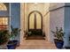 Arched double doors enhance the charm of this home's entry, flanked by potted plants at 5602 W Alameda Rd, Glendale, AZ 85310