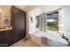 Bathroom featuring soaking tub, dark wood cabinets and shelving with backyard view at 6101 W Grandview Rd, Glendale, AZ 85306