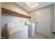 Functional laundry room with a skylight, wood beam detail, washer, dryer, and door to the exterior at 6101 W Grandview Rd, Glendale, AZ 85306