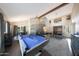 Spacious living room with a pool table, stairs, wooden beam, and views into the dining room and entryway at 6101 W Grandview Rd, Glendale, AZ 85306